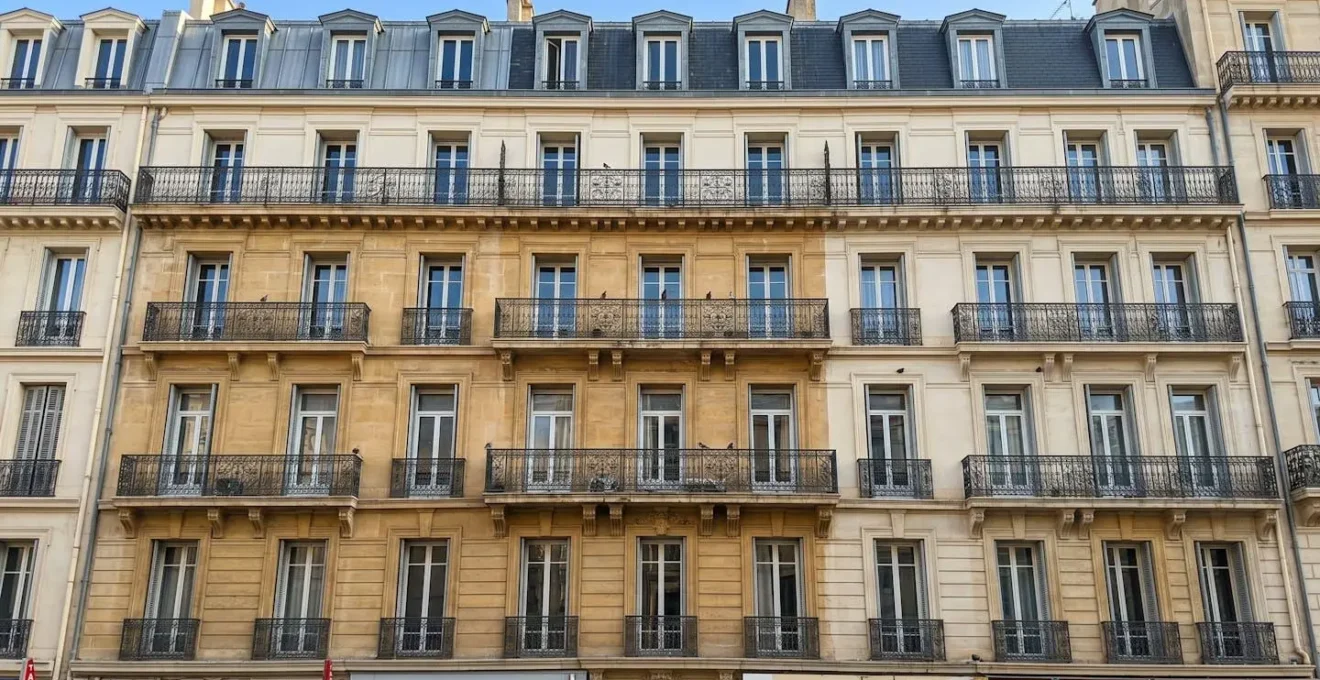 Façade d'immeuble marseillais avec balcons en fer forgé présentant des traces de fientes de pigeons sur les rambardes et rebords de fenêtres